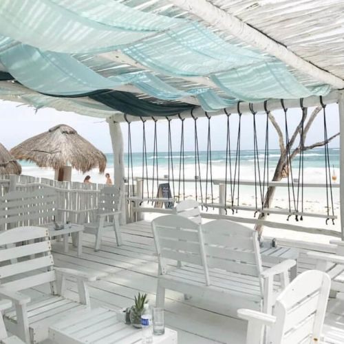 All-white lounge area at the beach, with chairs and wooden beach beds