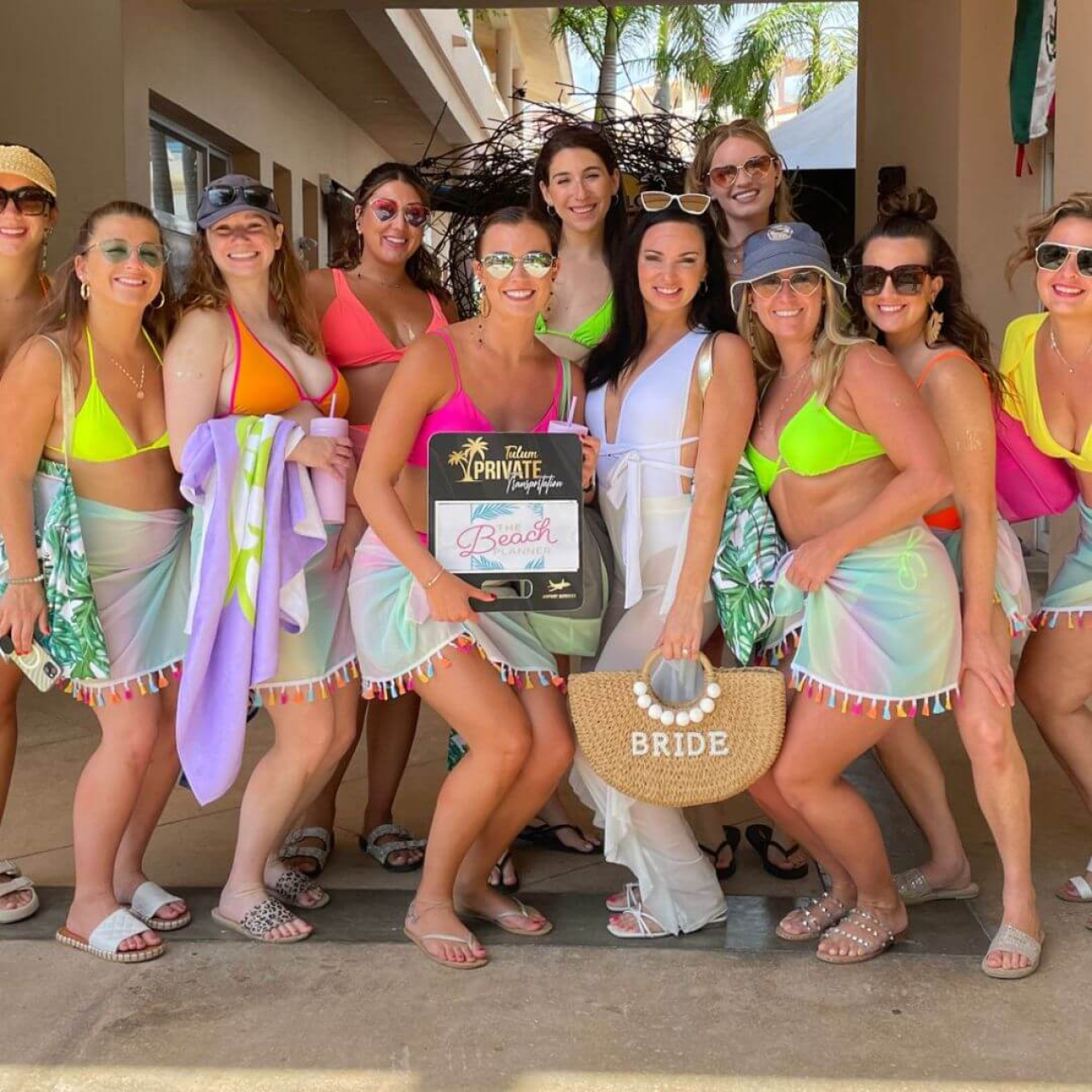 Bride and bachelorette posing with a sign from The Beach Planner