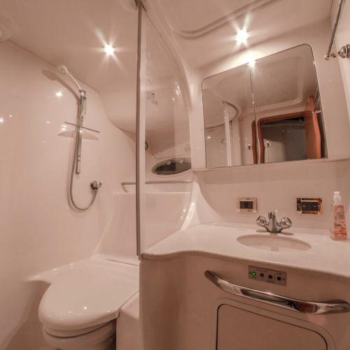 All white porcelain toilet, shower, and counter inside yacht