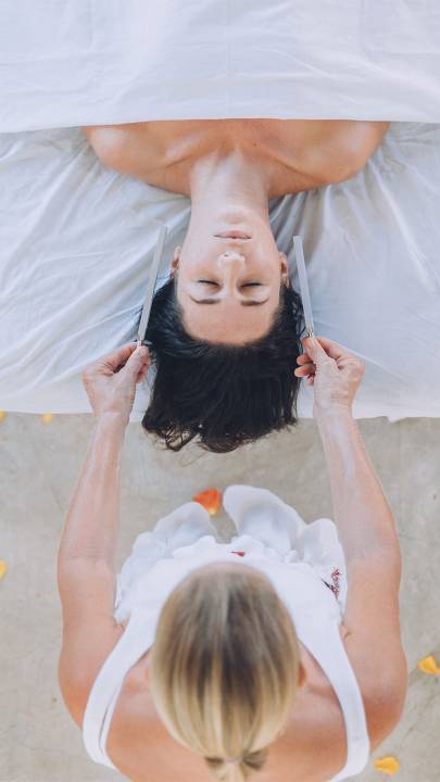 Woman covered by a white sheet to the neck, surrounded by orange petals
