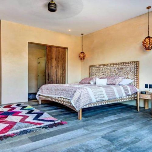 Bedroom, wood doors and bed in wood bed frame with designs carved and chevron carpet