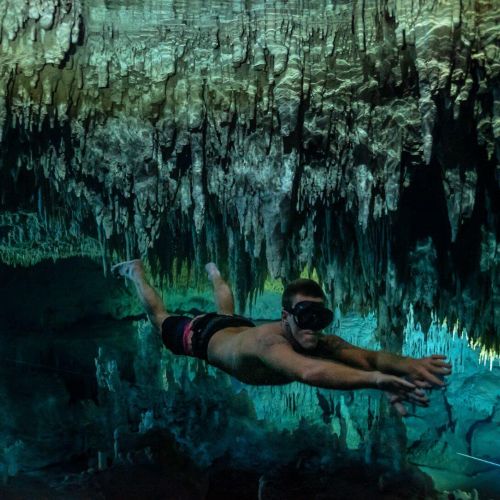 Person swimming underwater in a cenote