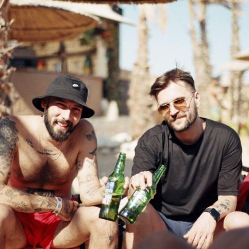 2 guys at the beach drinking beers