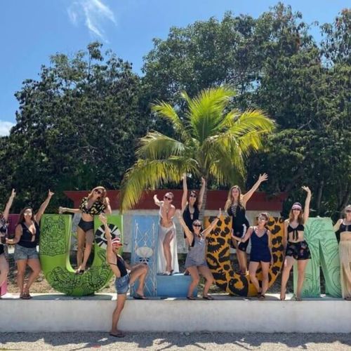 Women posing with the TULUM letters