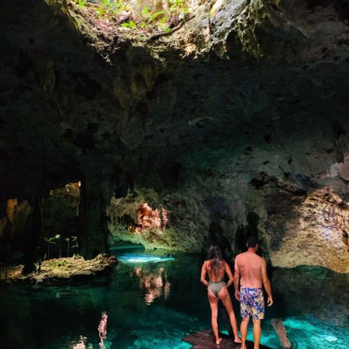 View of 2 people from the back standing on a deck in an underground cenote