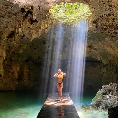 Girl posing in an underground cenote with sunlight showering her