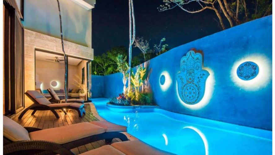 Pool side with hamsa hand decoration on the wall and lounge chairs